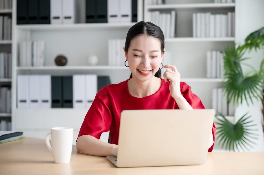 Smiling woman in front of laptop computer looking at website.