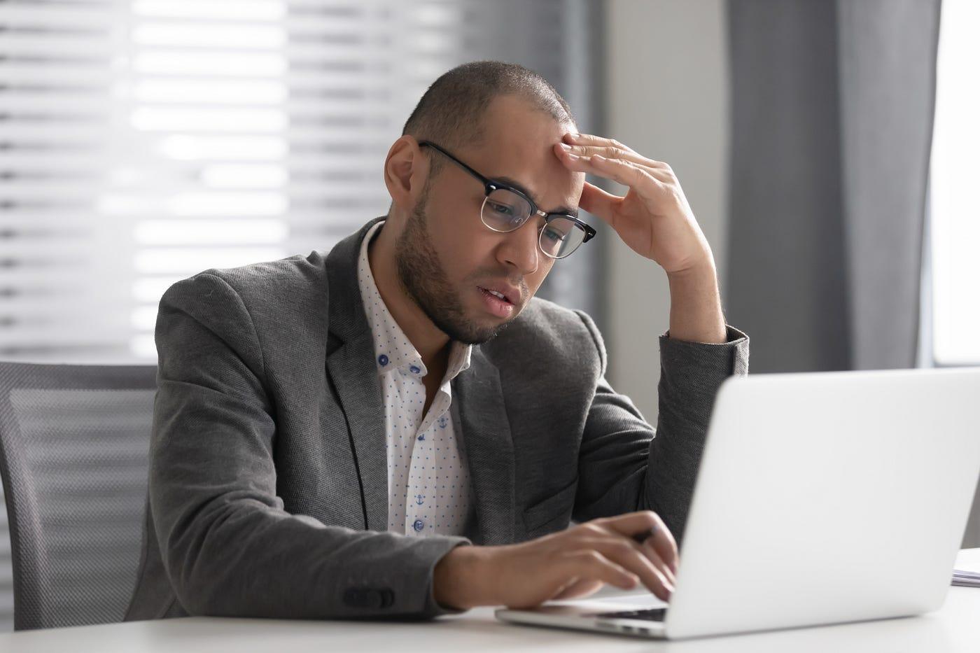 Man sitting at laptop computer with look of dread.